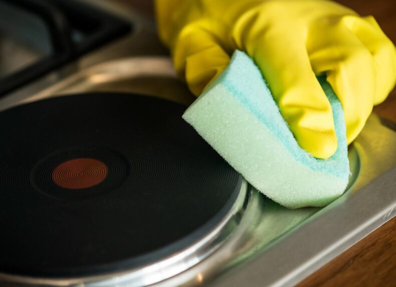 closeup-hands-wearing-gloves-wiping-stove-domestic-chores-concept