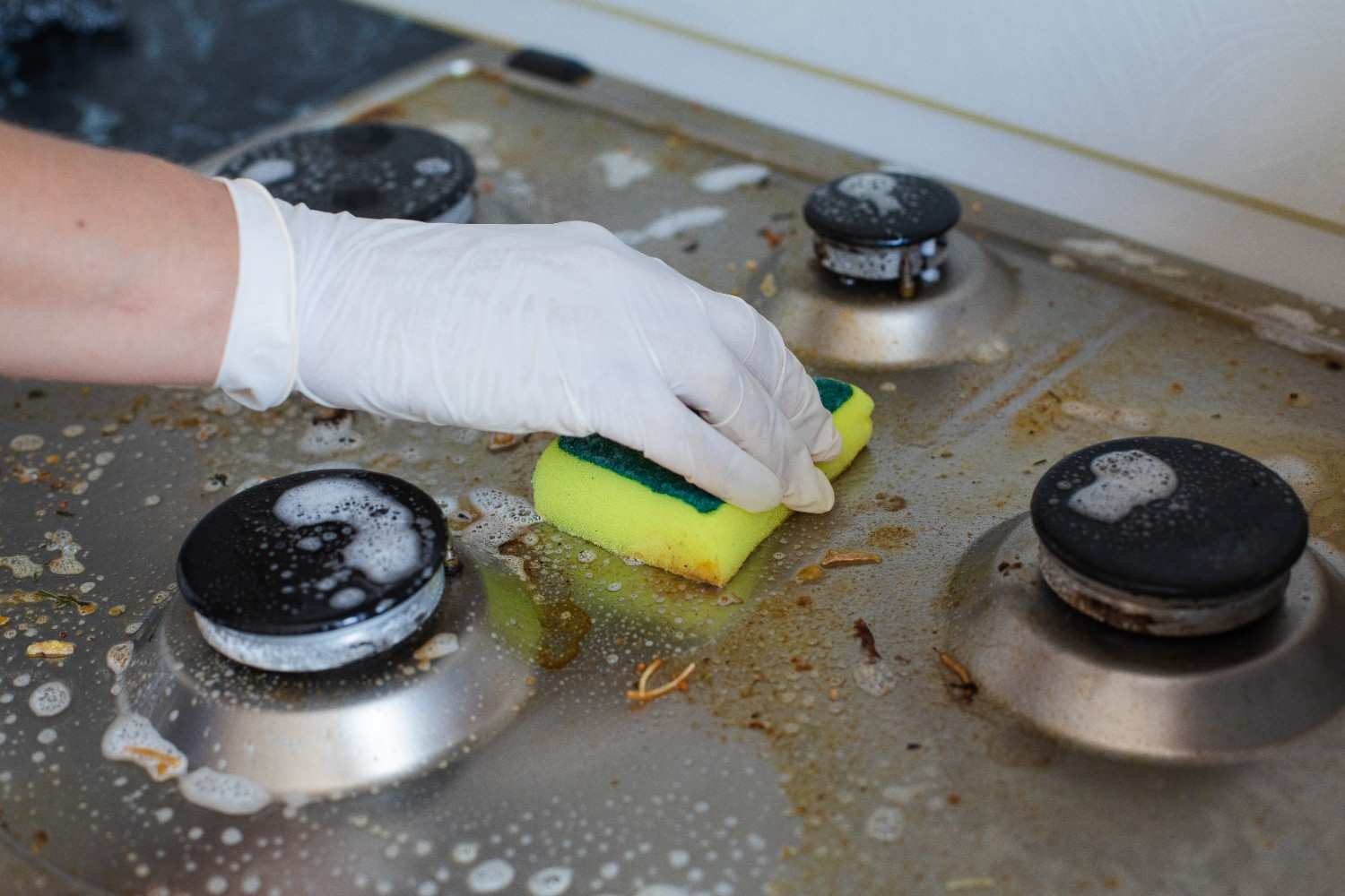 domestic-female-hand-wearing-gloves-cleaning-dirty-stove-after-cooking-using-sponge-washing-woman-housewife-enjoying-daily-household-closeup-top-view (1)
